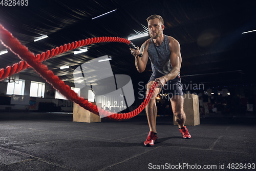 Image of Young healthy male athlete doing exercises in the gym