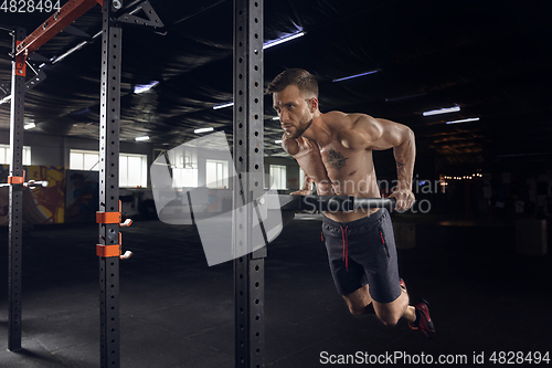 Image of Young healthy male athlete doing exercises in the gym