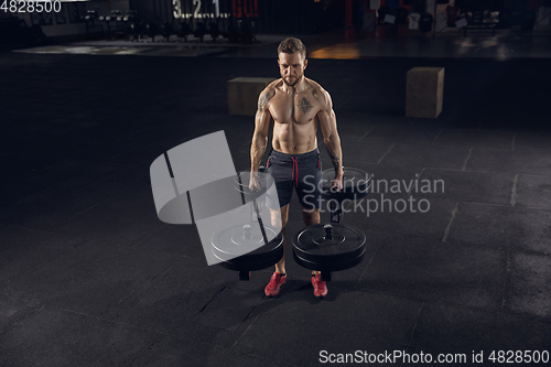 Image of Young healthy male athlete doing exercises in the gym