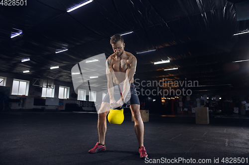 Image of Young healthy male athlete doing exercises in the gym