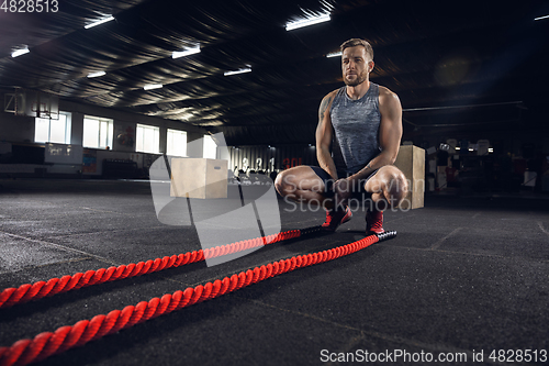 Image of Young healthy male athlete doing exercises in the gym