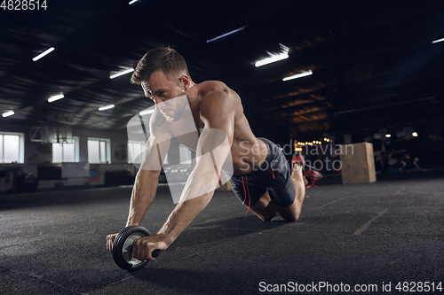 Image of Young healthy male athlete doing exercises in the gym