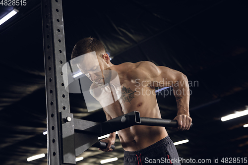 Image of Young healthy male athlete doing exercises in the gym