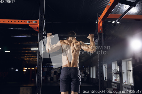 Image of Young healthy male athlete doing exercises in the gym