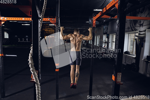 Image of Young healthy male athlete doing exercises in the gym