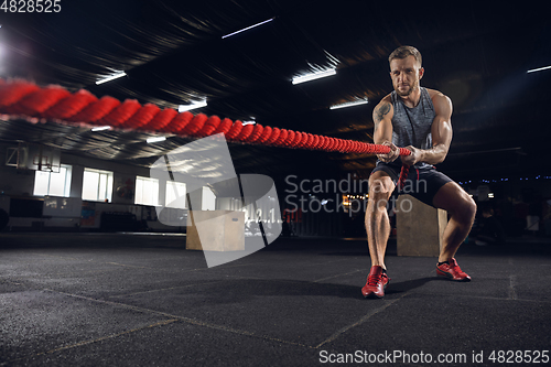 Image of Young healthy male athlete doing exercises in the gym