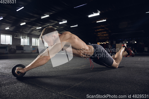 Image of Young healthy male athlete doing exercises in the gym