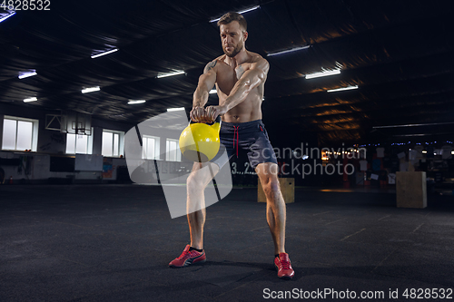 Image of Young healthy male athlete doing exercises in the gym