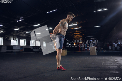 Image of Young healthy male athlete doing exercises in the gym