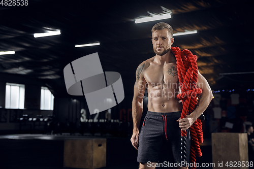 Image of Young healthy male athlete doing exercises in the gym