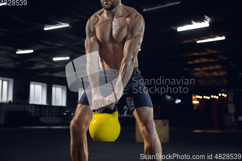 Image of Young healthy male athlete doing exercises in the gym