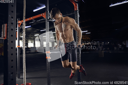 Image of Young healthy male athlete doing exercises in the gym