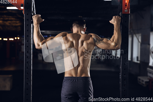 Image of Young healthy male athlete doing exercises in the gym