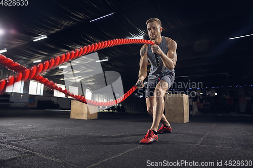 Image of Young healthy male athlete doing exercises in the gym