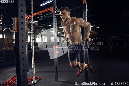 Image of Young healthy male athlete doing exercises in the gym