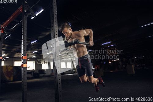 Image of Young healthy male athlete doing exercises in the gym