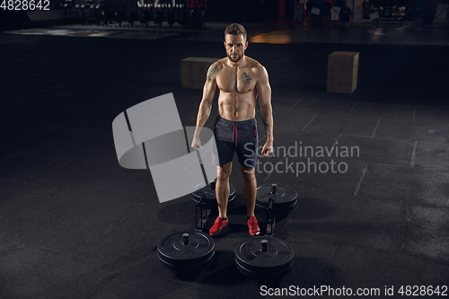 Image of Young healthy male athlete doing exercises in the gym