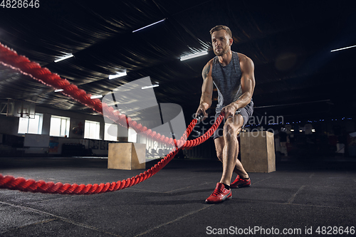 Image of Young healthy male athlete doing exercises in the gym