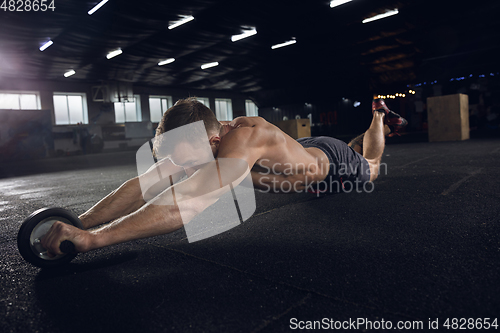 Image of Young healthy male athlete doing exercises in the gym