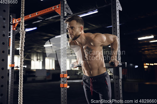 Image of Young healthy male athlete doing exercises in the gym