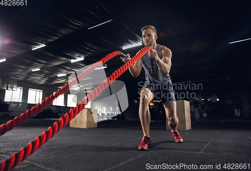 Image of Young healthy male athlete doing exercises in the gym