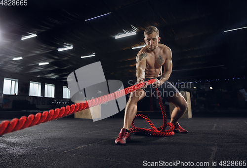 Image of Young healthy male athlete doing exercises in the gym