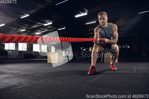 Image of Young healthy male athlete doing exercises in the gym