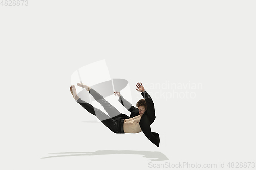 Image of Man in casual style clothes jumping and dancing isolated on white background. Art, motion, action, flexibility, inspiration concept. Flexible caucasian ballet dancer.