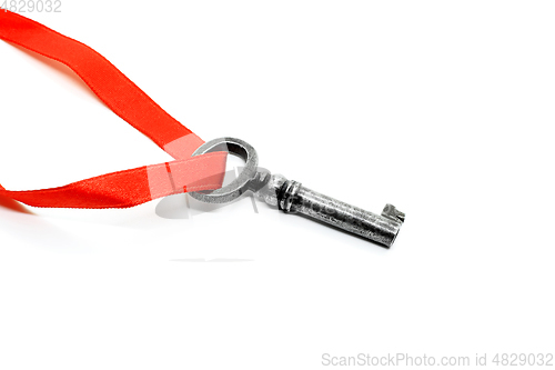 Image of Vintage silver key with red ribbon on white background