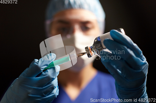 Image of doctor in face mask with syringe and medicine