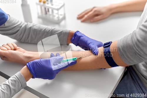 Image of doctor taking blood for test from patient's hand