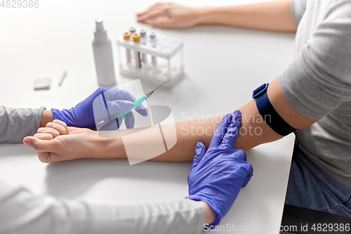 Image of doctor taking blood for test from patient's hand