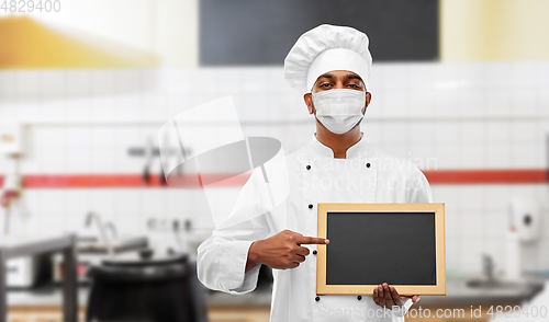 Image of chef in face mask with chalkboard at kitchen