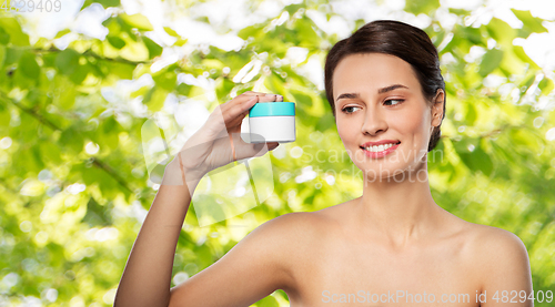 Image of happy young woman holding jar of cream