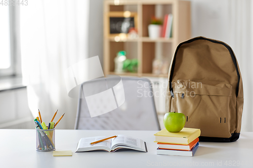 Image of books, apple and school supplies on table at home