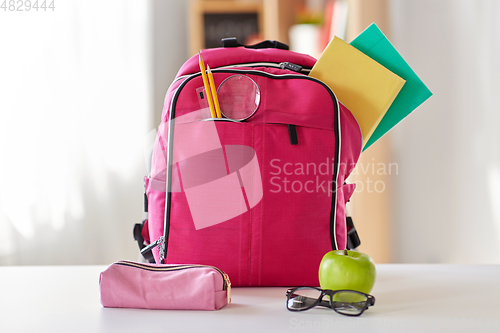 Image of pink backpack, apple and school supplies on table