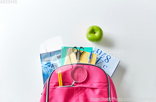 Image of backpack with books, school supplies and apple