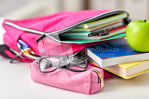 Image of backpack, apple and school supplies on table