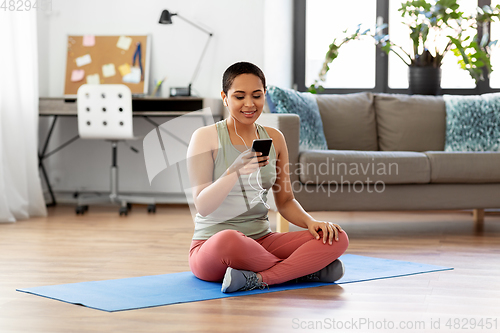 Image of woman with earphones and smartphone doing sports