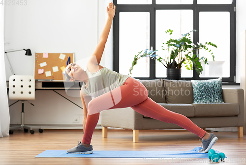 Image of woman doing extended side angle yoga pose at home