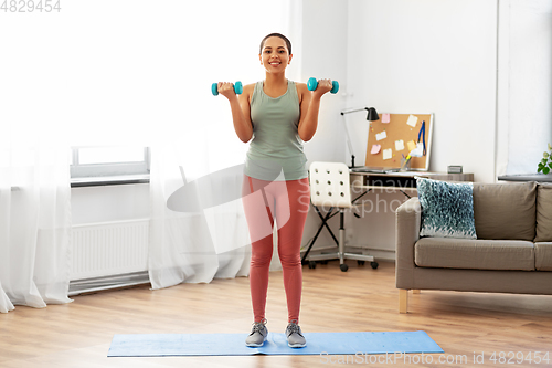 Image of african woman with dumbbells exercising at home