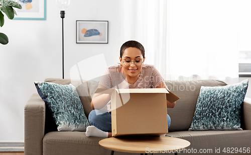 Image of african american woman opening parcel box at home