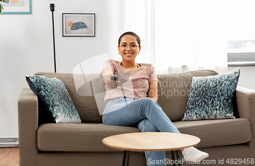 Image of happy african american woman watching tv at home