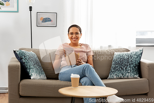 Image of african woman eating food with chopsticks at home