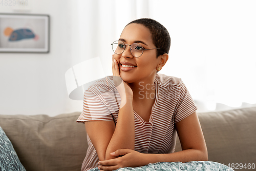 Image of african american woman in glasses sitting on sofa