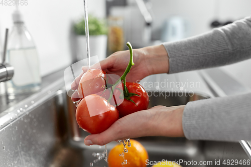 Image of woman washing fruits and vegetables in kitchen