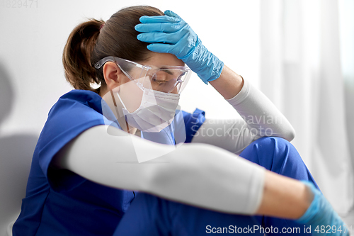 Image of sad doctor or nurse in face mask holding to head