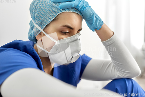 Image of sad doctor or nurse in face mask holding to head