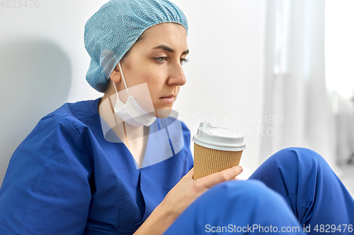 Image of sad doctor or nurse with cup of takeaway coffee