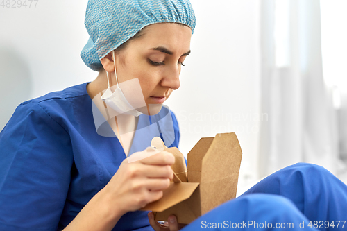 Image of sad doctor or nurse eating takeaway food from box